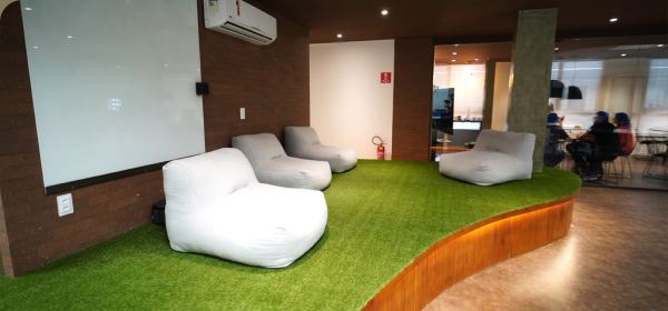 Sala de descompressão do Foccus Workplace com poltronas confortáveis sobre um piso de grama sintética.
