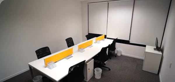 Sala privativa do Foccus Workplace equipada com bancadas, cadeiras e ar-condicionado.